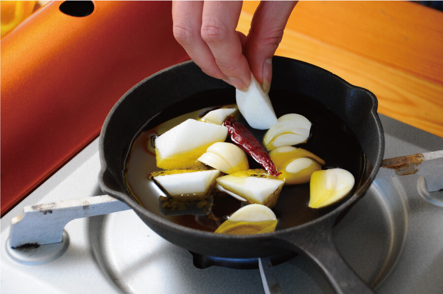 スキレットや小さめのフライパンに、オリーブオイル、ニンニク、赤唐辛子、塩、ナガイモを入れて弱火にかけます。