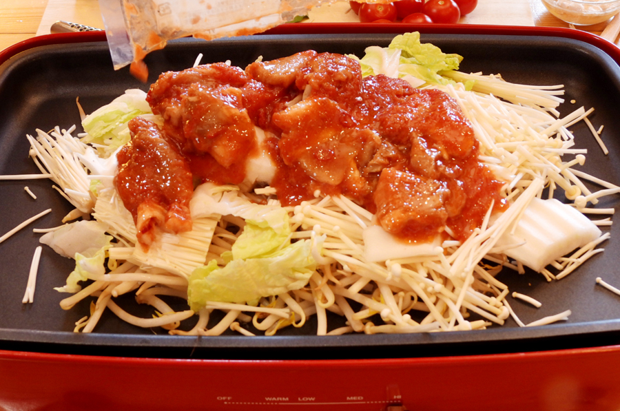 ２に３をかけて、上に豚肉、キムチを乗せて蓋をして加熱して蒸し焼きにします。